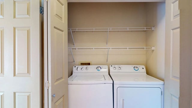 In-unit washer and dryer with shelving above.