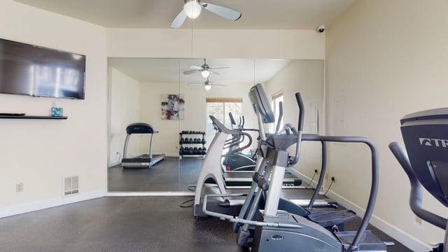 Fitness center with treadmills, elliptical machines, and weight racks.