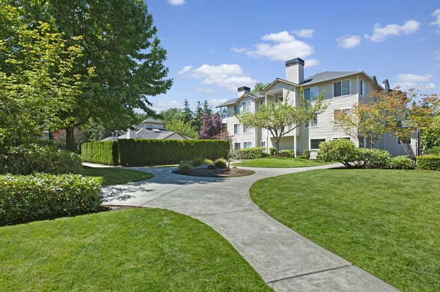 Exterior view of apartment buildings with manicured lawns and walkways.
