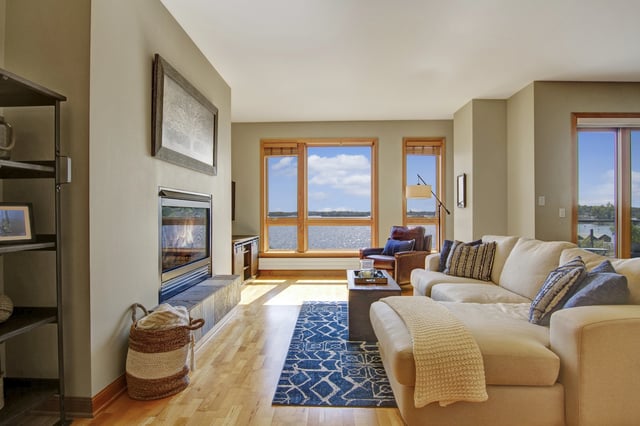 Living room with fireplace and large windows overlooking water.