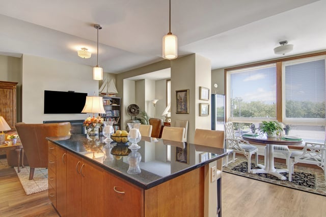 Modern kitchen island with granite countertop, bar stools, and pendant lights.