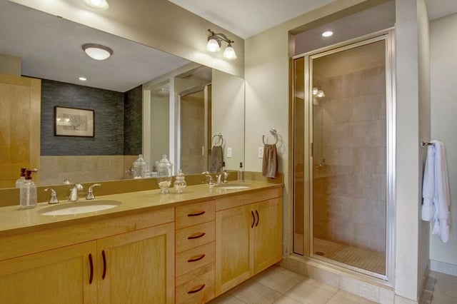Modern bathroom with double vanity and glass-enclosed shower.