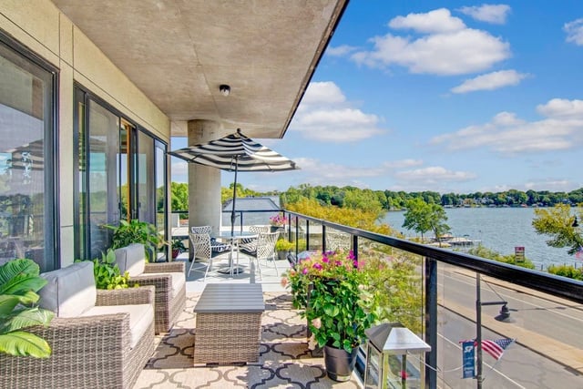 Balcony with seating and table overlooking a lake.