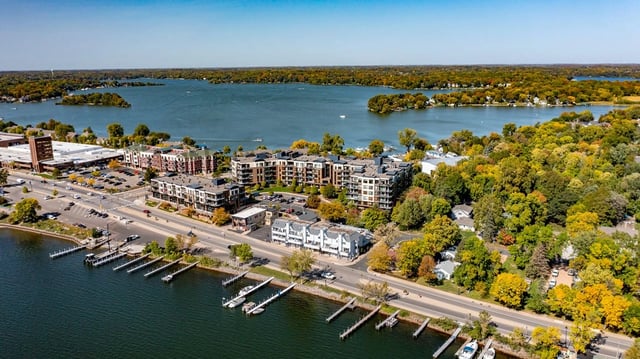 Aerial view of apartment buildings on a lake with fall foliage.