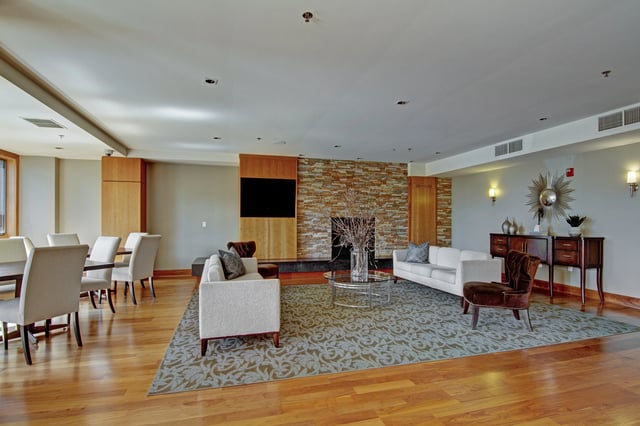 Spacious community lounge area with a fireplace, seating, and dining tables.