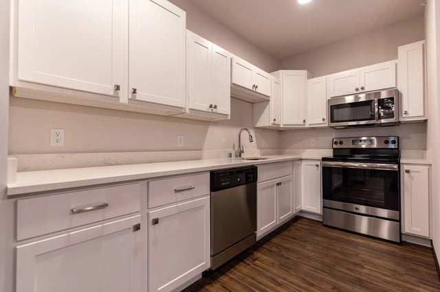 Modern kitchen with white cabinets, stainless steel appliances, and quartz countertops.