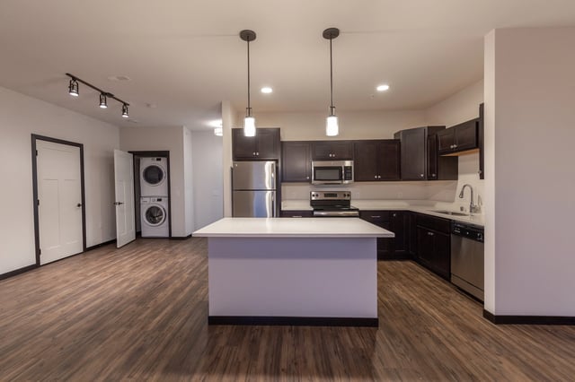 Kitchen with stainless steel appliances, dark cabinets, and an island with pendant lights.