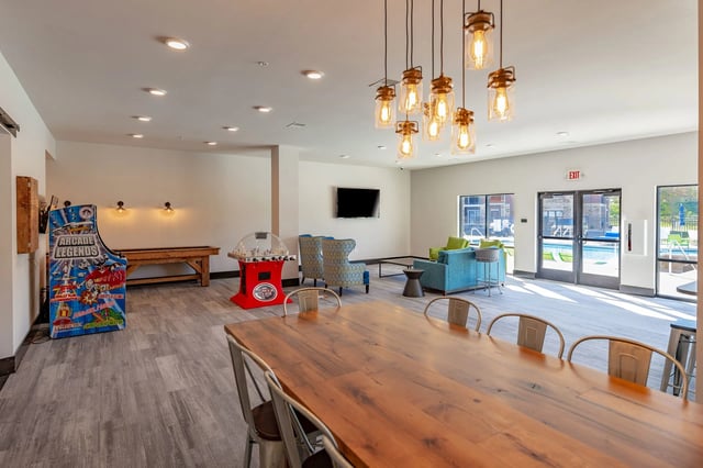 Community lounge with arcade games, foosball, pool table, seating, and pool view.