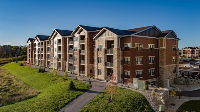 Exterior view of apartment building with brick and wood siding under a clear blue sky.
