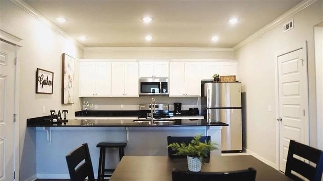 Modern kitchen with stainless steel appliances and white cabinets.
