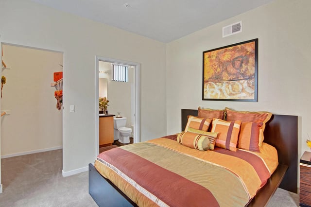 Bedroom with a queen-size bed, walk-in closet, and view of an en-suite bathroom.