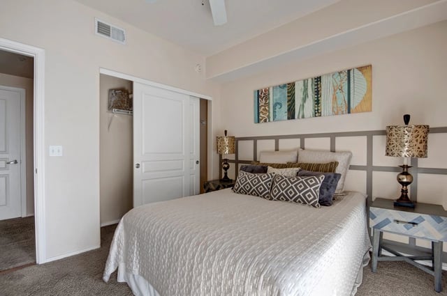 Bedroom with a king-size bed, sliding closet doors, and a decorative wall art.