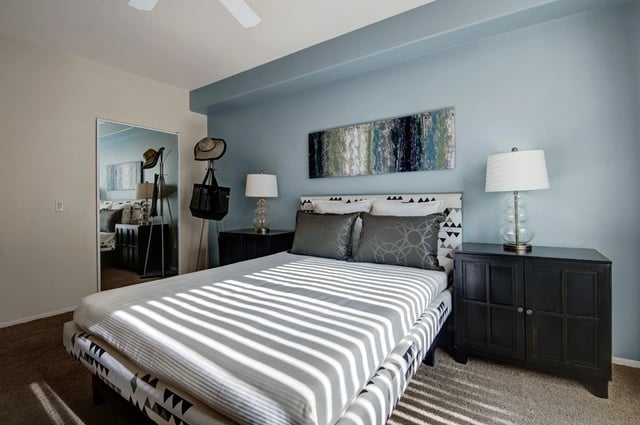 A cozy bedroom with a queen-sized bed, bedside tables, and a large mirror.