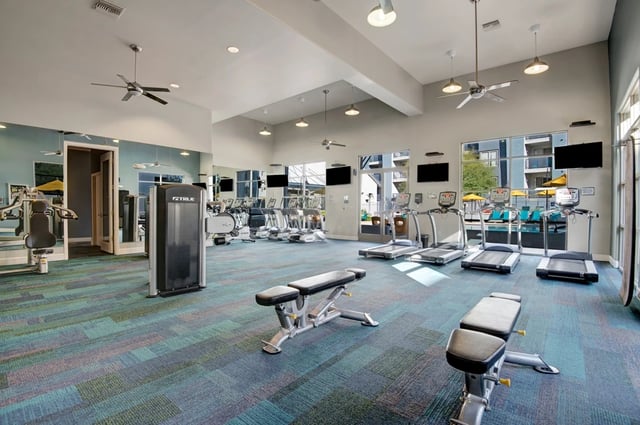 Fitness center with treadmills, ellipticals, weight machines, and benches.