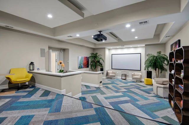 Home theater room with projector, large screen, and comfortable seating.