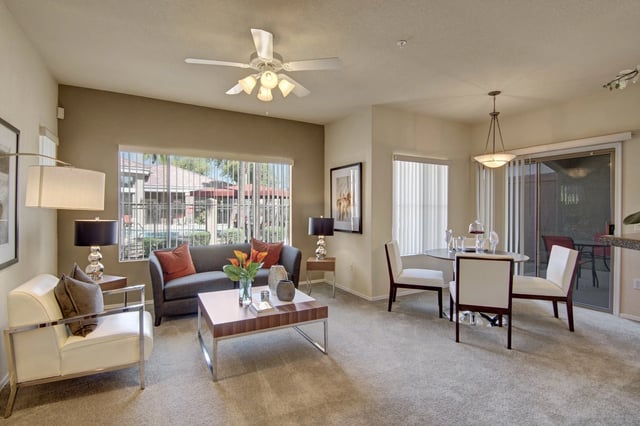 Living and dining area with a sofa, coffee table, and dining set, overlooking the pool.