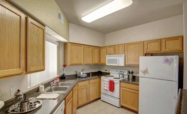 Kitchen with wood cabinets, white appliances, and granite countertops.