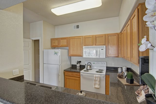 Kitchen with white refrigerator, white oven, microwave, and wood cabinets.