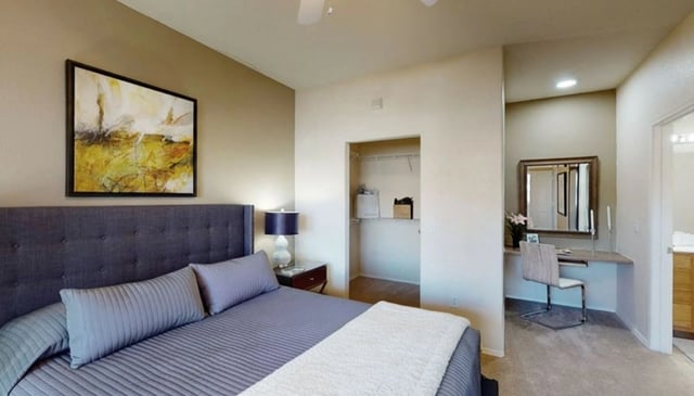 Bedroom with large bed, nightstand, closet, and vanity.