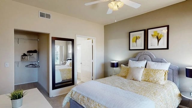 Bedroom with a queen-sized bed, closet, and a large mirror.