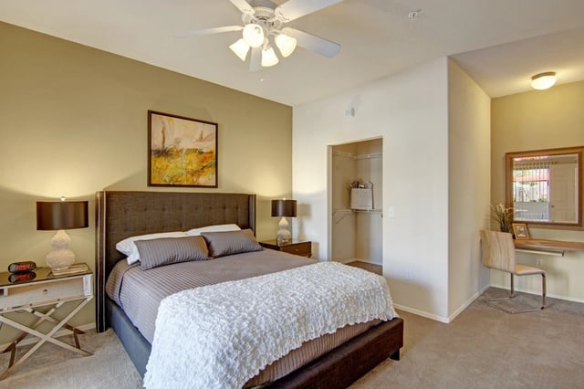 Spacious bedroom with a king-size bed, nightstands, ceiling fan, closet, and vanity area.