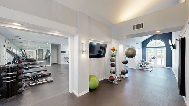 Gym equipment with treadmills, dumbbells, medicine balls, and stationary bikes.