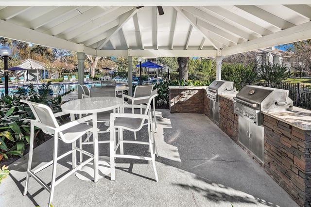 Outdoor kitchen with grills and seating area by the pool.