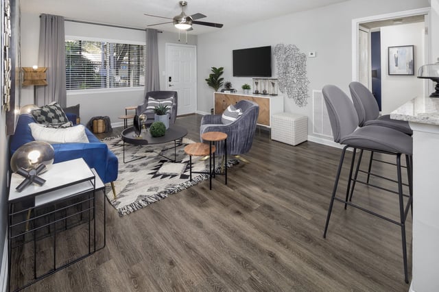 Living room with blue sofa, gray accent chairs, coffee table, and bar stools.