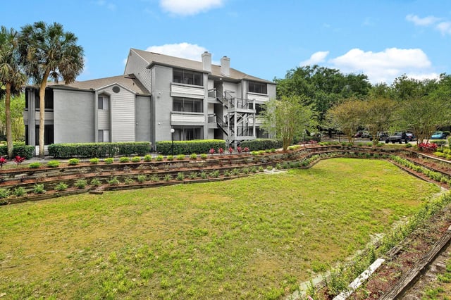 Exterior view of a multifamily apartment building with a grassy courtyard area in front.