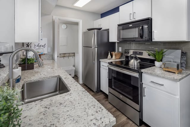 Modern kitchen with granite countertops, stainless steel appliances, and a laundry area.