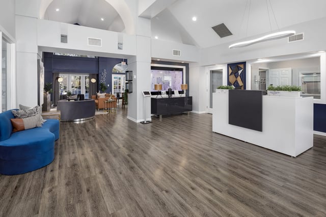 Modern leasing office lobby with a blue curved sofa and white reception desk.