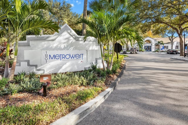 Metrowest Premier Apartments monument sign with palm trees and building in background.