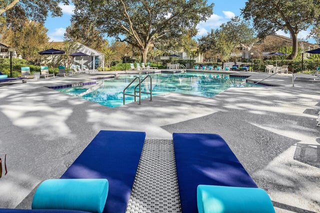 Resort-style pool with lounge chairs and umbrellas.