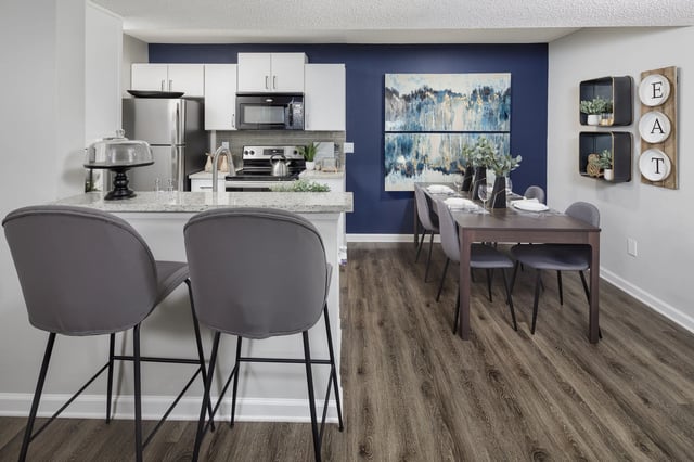 Modern kitchen and dining area with gray bar stools and a dark wood dining table.