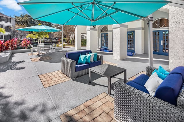 Outdoor lounge area with blue sofas, tables, and umbrellas.