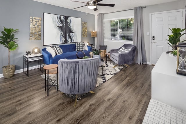 Stylish living room with blue sofa, grey armchairs, coffee table, and modern decor.
