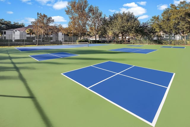 Multiple tennis and pickleball courts with blue and green surfaces.