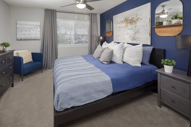 Modern bedroom with a king-size bed, navy accent wall, and a comfortable armchair.