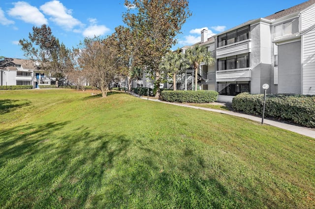 Exterior view of apartment buildings with green lawn and trees.