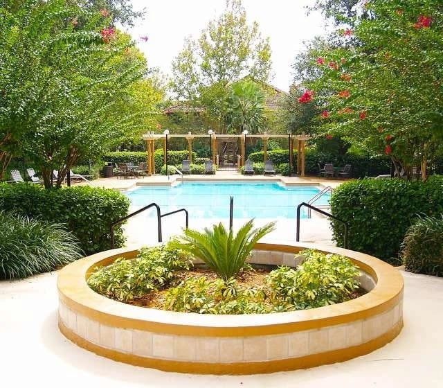 Outdoor swimming pool with lounge chairs and lush landscaping.