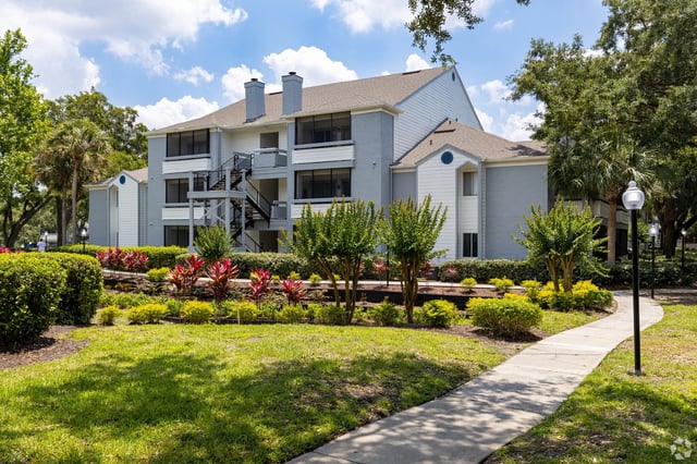 Exterior view of apartment building with lush landscaping and a walking path.