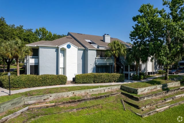 Exterior view of apartment building with palm trees and manicured landscaping.