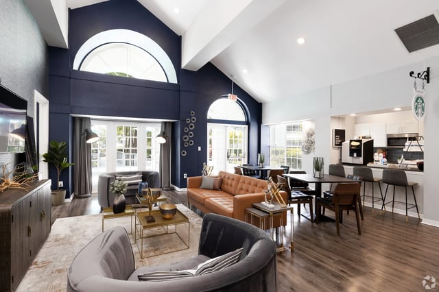 Modern lounge area with plush seating, coffee bar, and large arched windows.