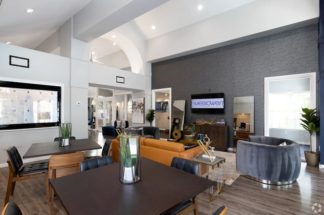 The MetroWest apartment building's communal lounge area featuring seating, tables, and a TV.