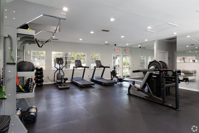 Interior of a well-equipped fitness center with treadmills, an elliptical, a rowing machine, and weight machines.