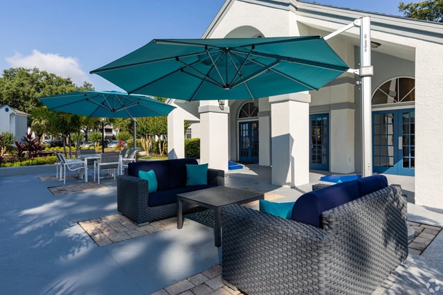 Outdoor seating area with blue umbrellas, lounge chairs, and tables.