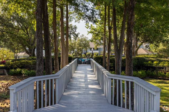 Wooden bridge leading to a pool area with lounge chairs.