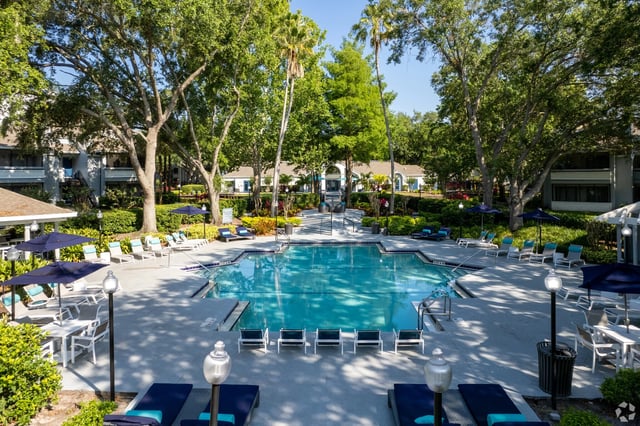 Outdoor swimming pool with lounge chairs and umbrellas.