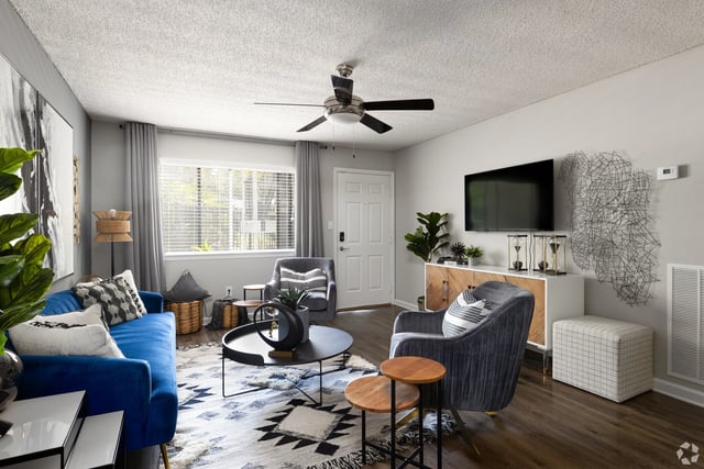 Modern living room with blue sofa, gray armchairs, coffee table, and TV.
