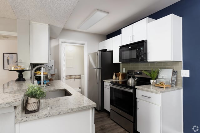 Modern kitchen with stainless steel appliances, white cabinets, and granite countertops.
